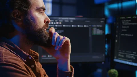 Software engineer puzzled in front of computer screen while writing complex code Stock Footage 265336622