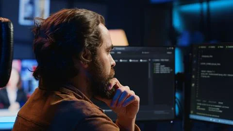 Software engineer puzzled in front of computer screen while writing complex code Stock-Fotos