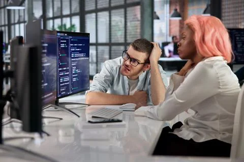 Software Engineer Quietly Fixes Broken Code While Stressed At Busy Desk. Stockfoto's