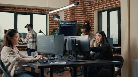 Software engineer typing source code on computer keyboard while colleagues sit Stock Photos