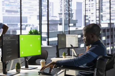 Software engineer in wheelchair checking code on mockup PC 写真素材