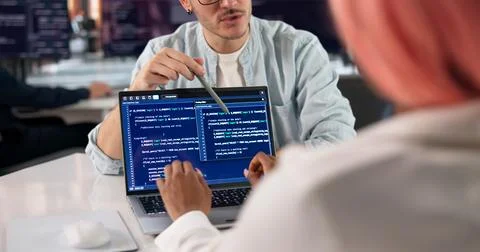 Software Engineer Writes Code On Laptop While Discussing Project With Team. Fotos Stock