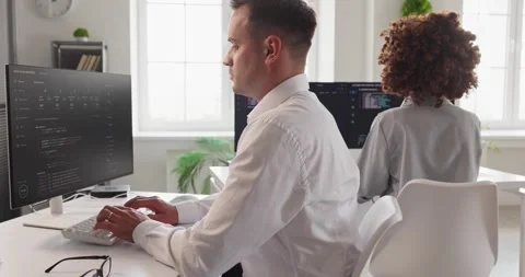Software engineers in bright office, reviewing code on computer screens together Vídeo Stock 338289732