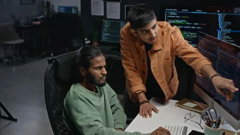 Software Engineers Discussing Code on Computer Monitor Stockbeeldmateriaal 348367276