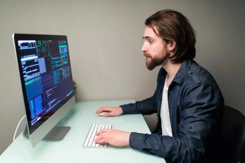 Software man developer on the computer screen and is analyzing the code. Stock Photos