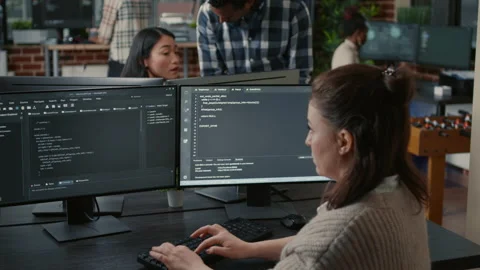 Software programer writing code in front of multiple computer screens Stock Footage 168250175
