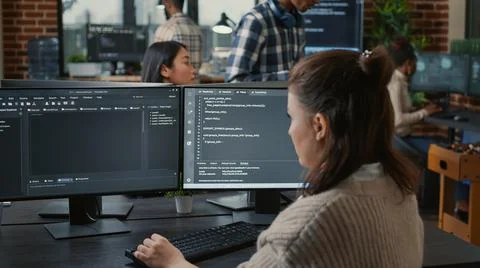 Software programer writing code in front of multiple computer screens Stock-Fotos