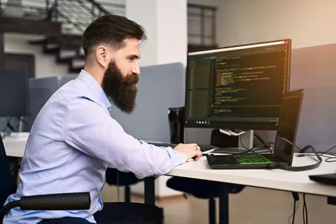 Software programming. Bearded man working on computer in IT office, sitting at Stockfoto's