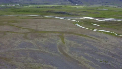 Soil and grass field with river, revealing a mountain with snow Stock Footage 138738556