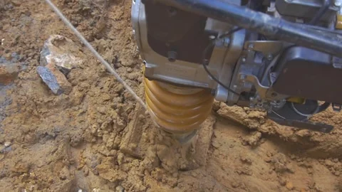 Soil compactor hammering on dry mud at a construction site Stock Footage 255684387