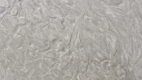 Soil texture due to small water flows on the beach 库存照片