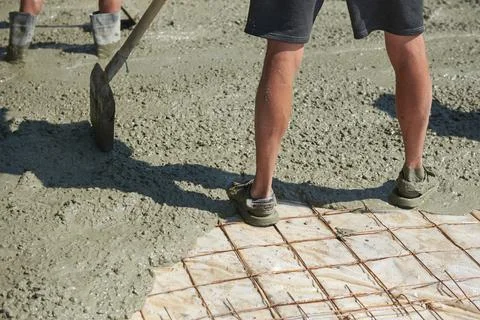 Soiled construction worker stands with his feet in concrete on a construction Foto stock