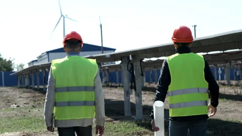 Solar and wind clean power engineers walk past solarcells Stock Footage 165318613
