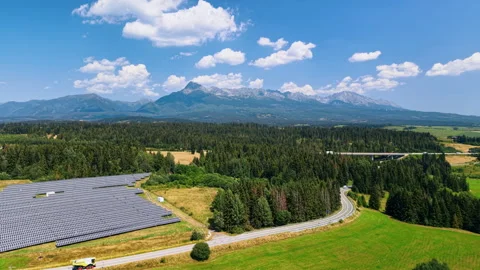 Solar array and curving road beneath the High Tatras. Panel rows fill the lower Vídeo Stock 346190848
