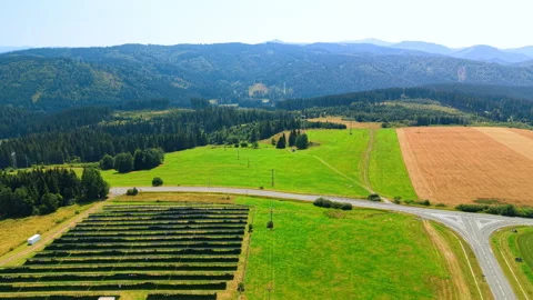 Solar array beside a rural road junction and fields. Dark panel rows stand on Vídeo Stock 346190816