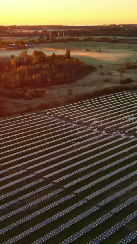 A solar array in the foreground, set against a rural landscape bathed in the Stock Footage 321039753