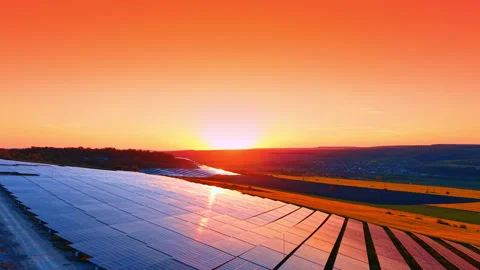 Solar array reflecting sunset over agricultural valley, sun forms orange bands Video stock 337913194