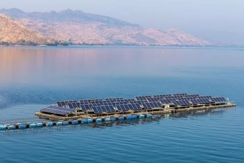 Solar cell lines arranged in rows on a river with a mountain background Stock Photos