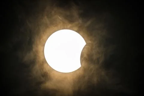 Solar eclipse in action, including atmospheric clouds Stock Photos