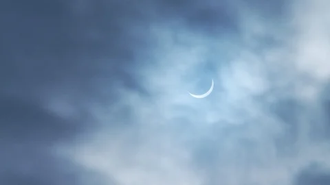 Solar Eclipse in a cloudy light blue sky Stock Footage 112513570