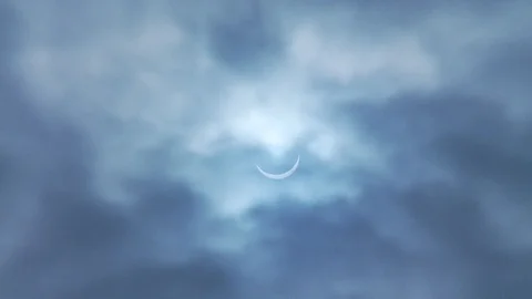 Solar Eclipse in a cloudy light blue sky 2 Stock Footage 112514145