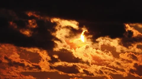 Solar eclipse during sunset with dark clouds moving across the glowing sky. Stock Footage 342172625
