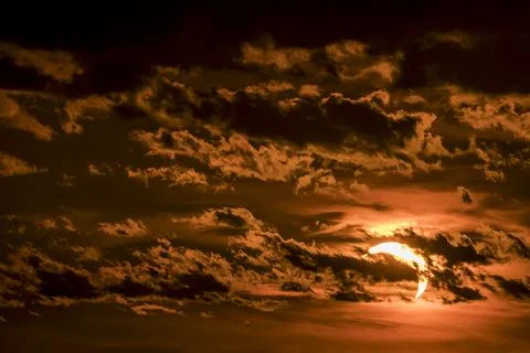 Solar eclipse during sunset with dark clouds filling the sky Stock Photos