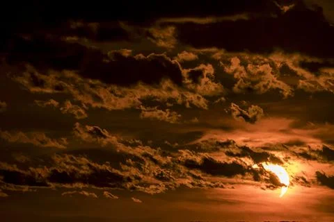 Solar eclipse during sunset with dark clouds filling the evening sky. Stock Photos