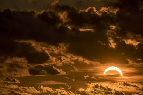 Solar eclipse during sunset with moon covering sun and dark clouds above. Stock-Fotos