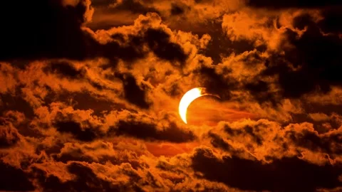 Solar eclipse during sunset with orange clouds covering sun. Stock Footage 342173386
