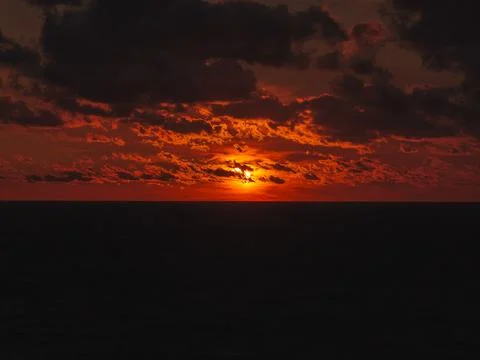 Solar eclipse during sunset over ocean with dark clouds Stock Photos
