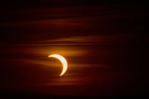 Solar eclipse over the landscape, showing dark lunar silhouette gliding acros Фото