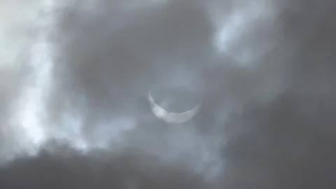 Solar Eclipse with partial totality is seen through dramatic gray cloudy ski Stock Footage 271303593