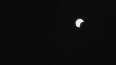 Solar eclipse partially covering the moon in the night sky over Little Stock Footage 276838006