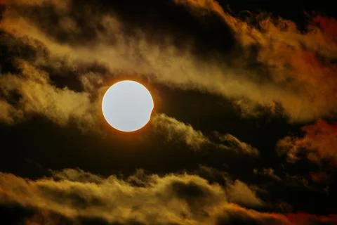 Solar eclipse partially obscured by clouds, with the sun's bright corona vi.. Stock Photos