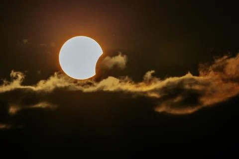 Solar eclipse partially obscured by clouds, with the sun's corona visible a.. Stock Photos
