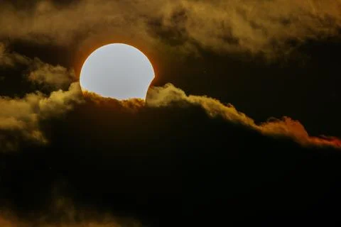 Solar eclipse partially obscured by dark clouds with a bright halo around t.. Stock Photos