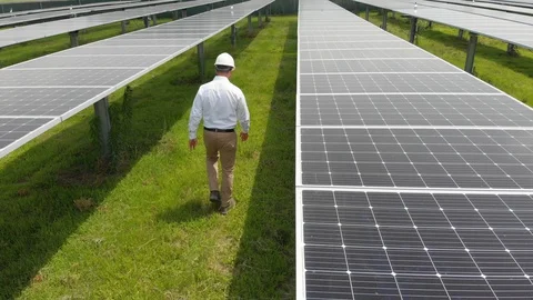 Solar engineer walks through a field of panels Stock Footage 129765012
