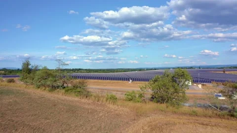 Solar farm: flying over fields, trees, rows solar panels (color graded) Stock Footage 153942481