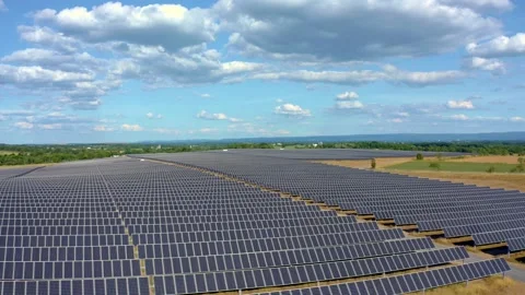 Solar farm: low aerial across rows of solar panels sunny (color graded) Stock Footage 153942453