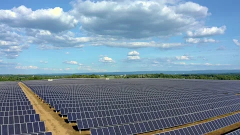 Solar farm: low over rows solar panels dramatic tilt down (color graded) Stock Footage 153942477