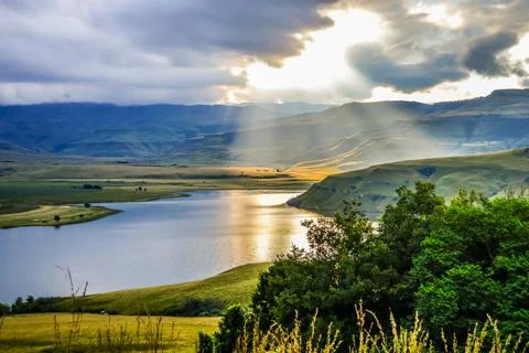 Solar flare and sun rays over Maloti Drakensberg mountains and bell park dam Stock Photos
