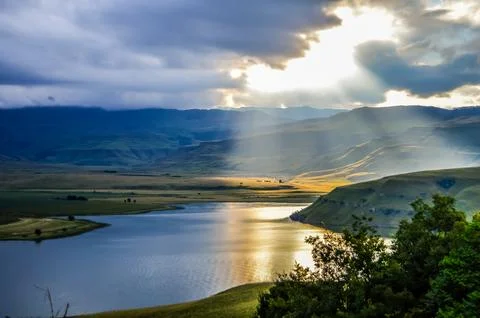 Solar flare and sun rays over Maloti Drakensberg mountains and bell park dam Stock Photos