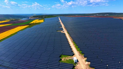 Solar modules lining a central access road, panel blocks cross farmland under Stock Footage 337912701