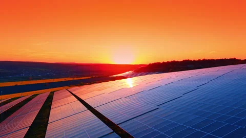 Solar modules reflecting sunset across rolling farmland, aerial angle shows Stock Footage 337913255