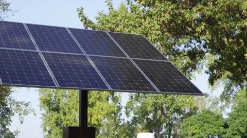 Solar panel against a background of green trees and blue sky on a sunny day Vídeo Stock 253504211