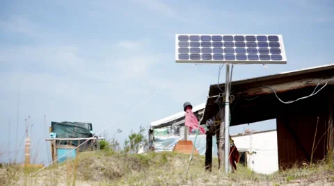 Solar panel and makeshift shelters on beach Stock Footage 63302706