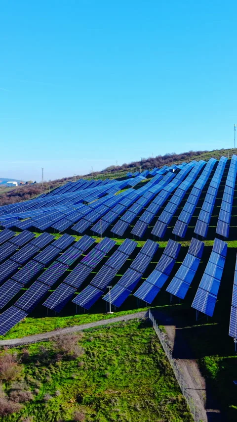 Solar panel array on green hillside under clear blue sky Vertical video. Stock Footage 332346885