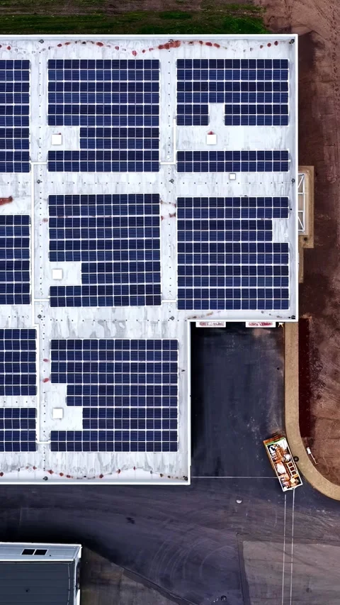 Solar panel array on industrial rooftop next to cleared construction land Stock Footage 336718385