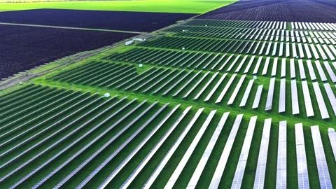 Solar panel array stretches across the green fields under clear skies Stock Footage 325088321